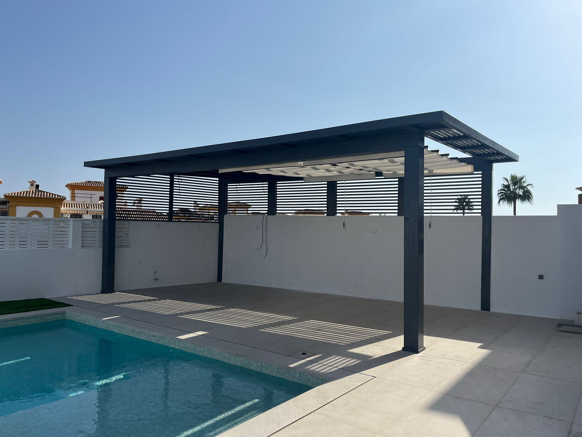Pérgola de madera de diseño moderno con lasur gris y techo retráctil en jardín.