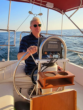 man at helm of sailboat