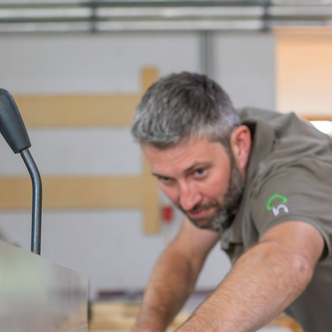 Ein Mann lässt ein Holzstück durch eine Maschine laufen