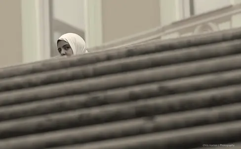 Woman in a white hijab walking past stone steps in Rome, Italy.