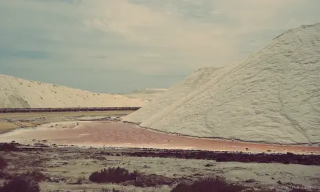 Large salt dunes with pink water below in La Camargue, France