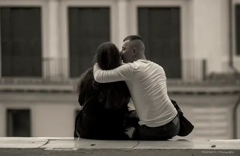 Couple sharing a kiss in front of a church in Rome, Italy.