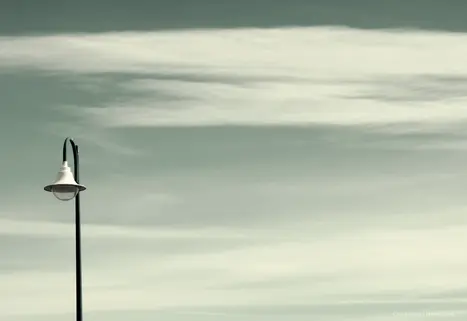 Street lamp under a soft blue sky with subtle clouds in Carnon, France.