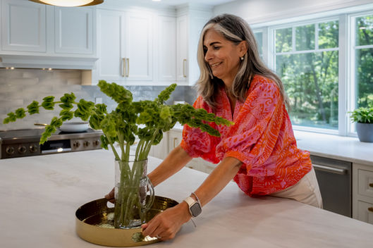 Woman arranging green flowers in a kitchen in Littleton.