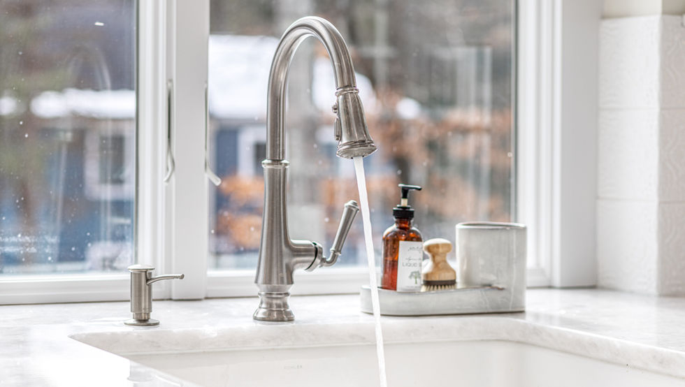 Modern kitchen faucet with water running into a white sink