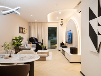 Modern minimalist living room at The Warren CCK featuring a curved TV feature wall, light wood cabinetry, and a neutral cream color palette.