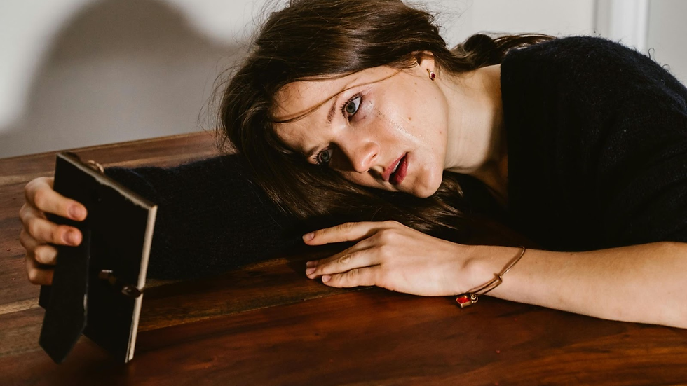 A woman with a black t-shirt lay on the table, her hand holding a frame.