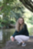 Frau hockt lächelnd an einem Bach im Wald.JPG