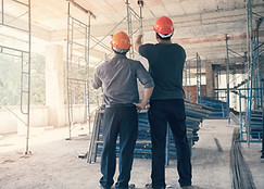 Two men in hardhats inside an unfinished building