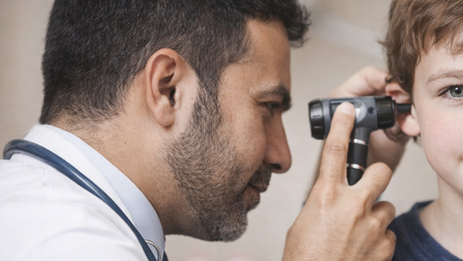 Close up of man checking a young boy's ear health