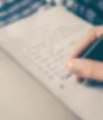 A person writing a to-do list in a bullet journal.