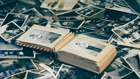 Fotografie sparse in bianco e nero su cui c'è un album aperto con altre due istantanee - https://pixabay.com/photos/photos-nostalgia-retro-photography-7666143/