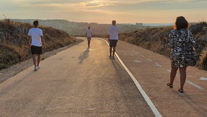Una strada, sfondo Matera, quattro giovani che camminano.