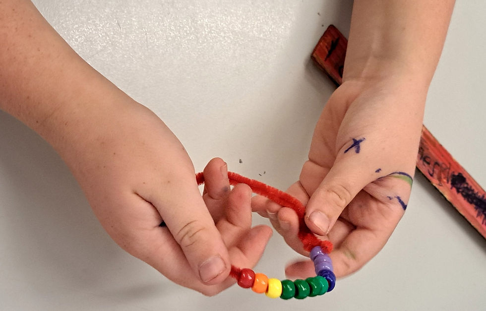 child's hands making a mindfulness tool from pipe cleaners and beads