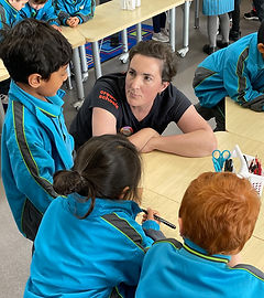 Naomi helping young students at a classroom desk