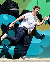 Shona standing on one leg being silly in front of a mural
