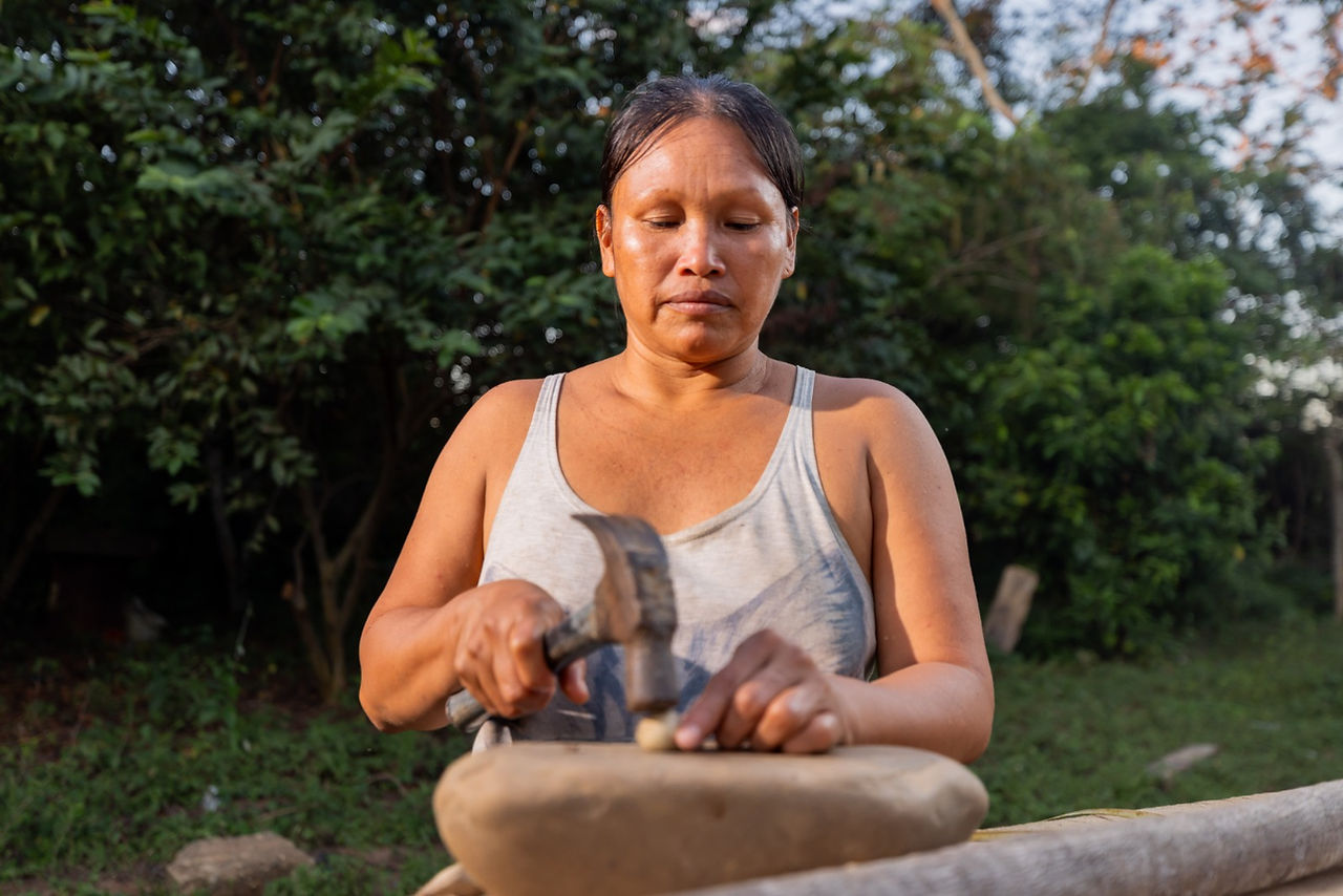 Amazonian woman processing murumuru seeds by hand, adding value to a sustainable non-timber forest product.