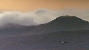 Mist spills over the top of the Pentland Hills, with golden sun rising behind,