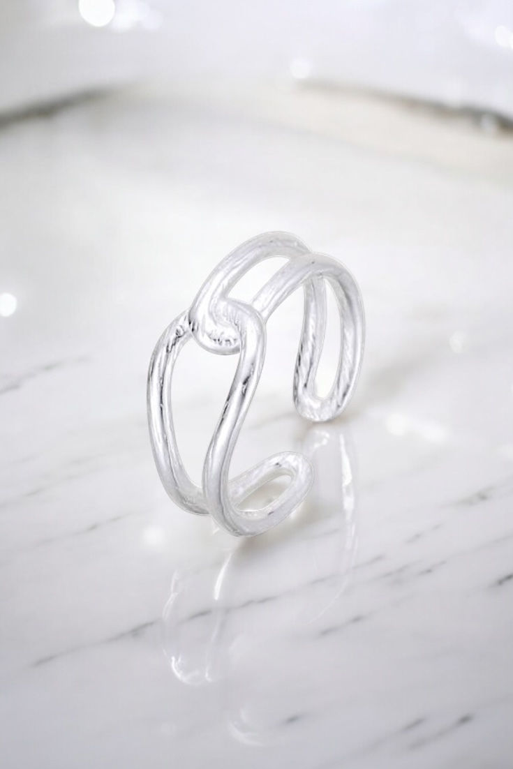 תמונה של טבעת שעשויה משתי חוליות משולבות מכסף על רקע של שיש אפור לבן