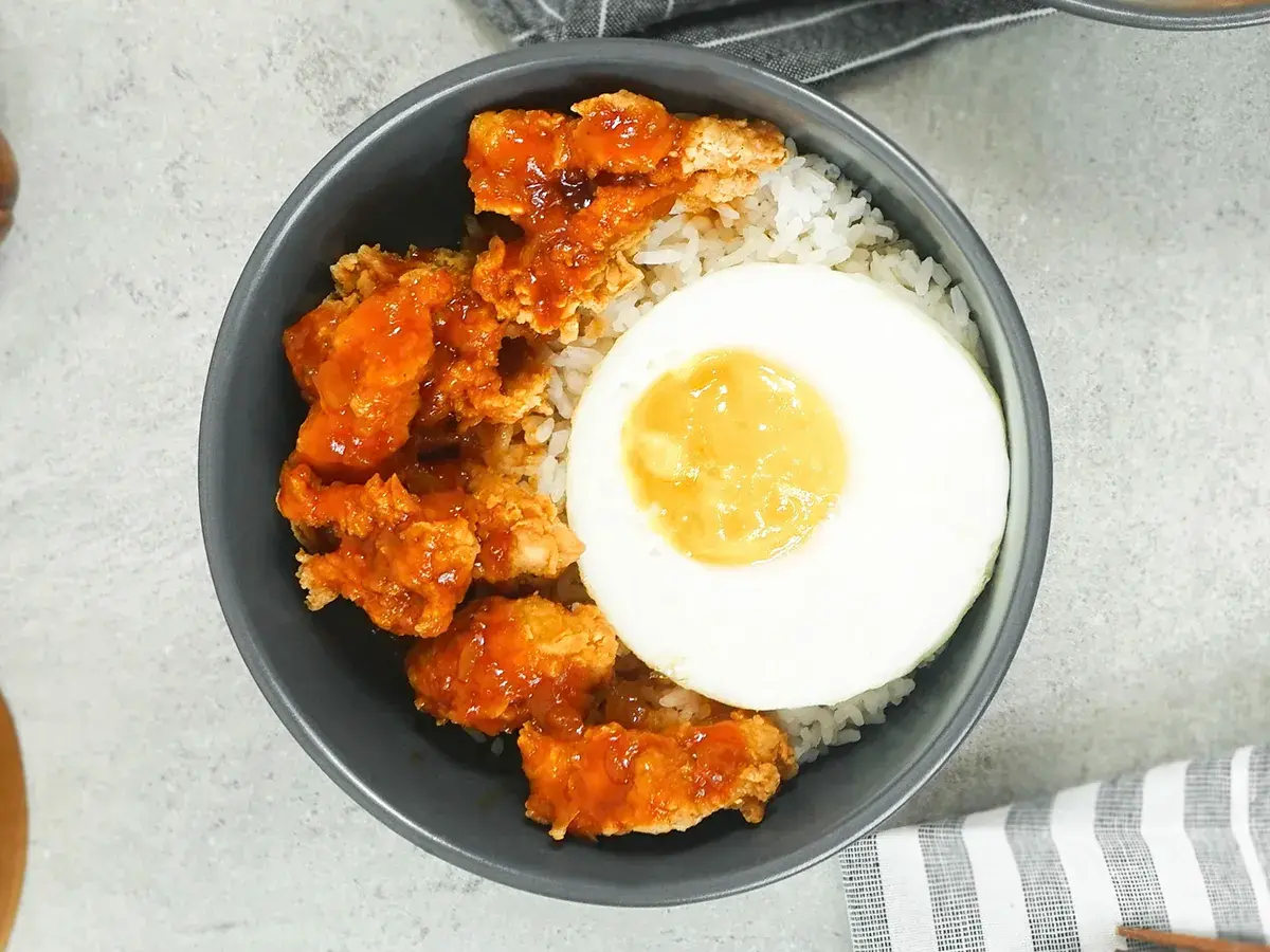 Brown Butter Chicken Rice Bowl dengan nasi hangat, ayam filet saus butter gurih manis, dan telur setengah matang atau matang.