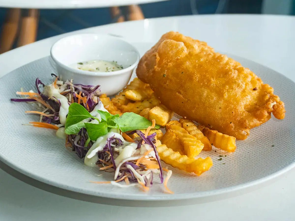 Fish and chips dori dengan kentang goreng dan salad.
