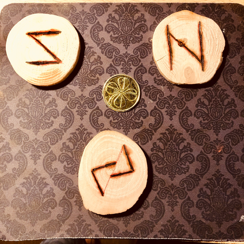 Wooden coins emblazoned with Nordic runes and a "golden" coin.