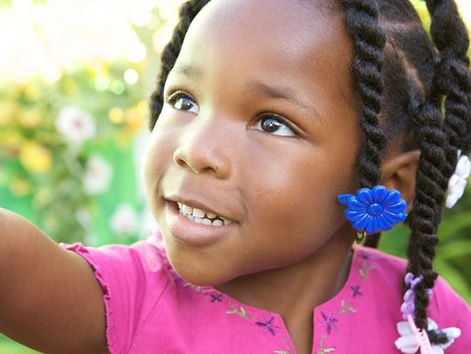 Une petite fille aux cheveux crépus qui sourit