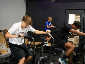 Youth athletes completing air-bike intervals during Cedar Park Athlete Training