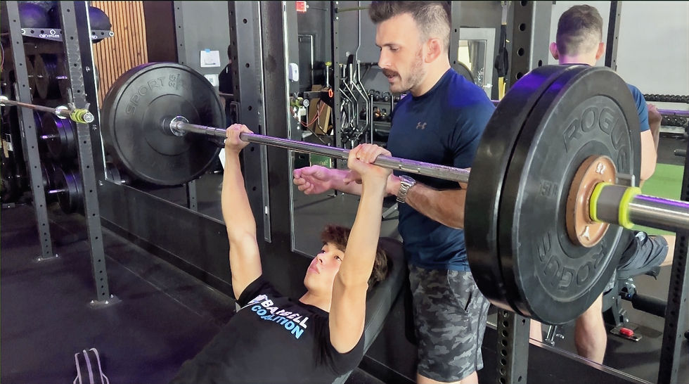 coach spotting youth athlete on bench press