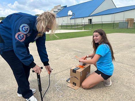 A guest astronaut helping a student prepare a rocket for launch