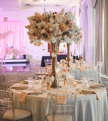 Luxury wedding reception with crystal chairs, tall floral centerpieces, soft uplighting, and elegant table settings.