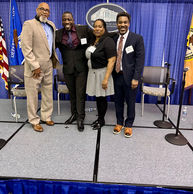 Four professionals posing on a stage with blue curtains.
