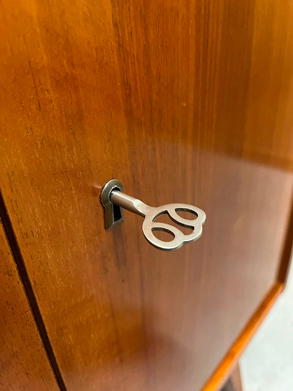 Miniaturbild: silberner vintage schlüssl mit messing schlüsselschild an einer mid century holztür