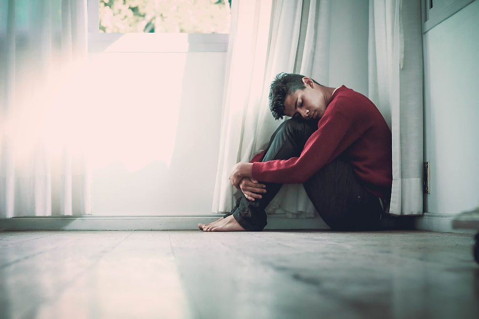 Boy in the corner of the light lit room looking sad