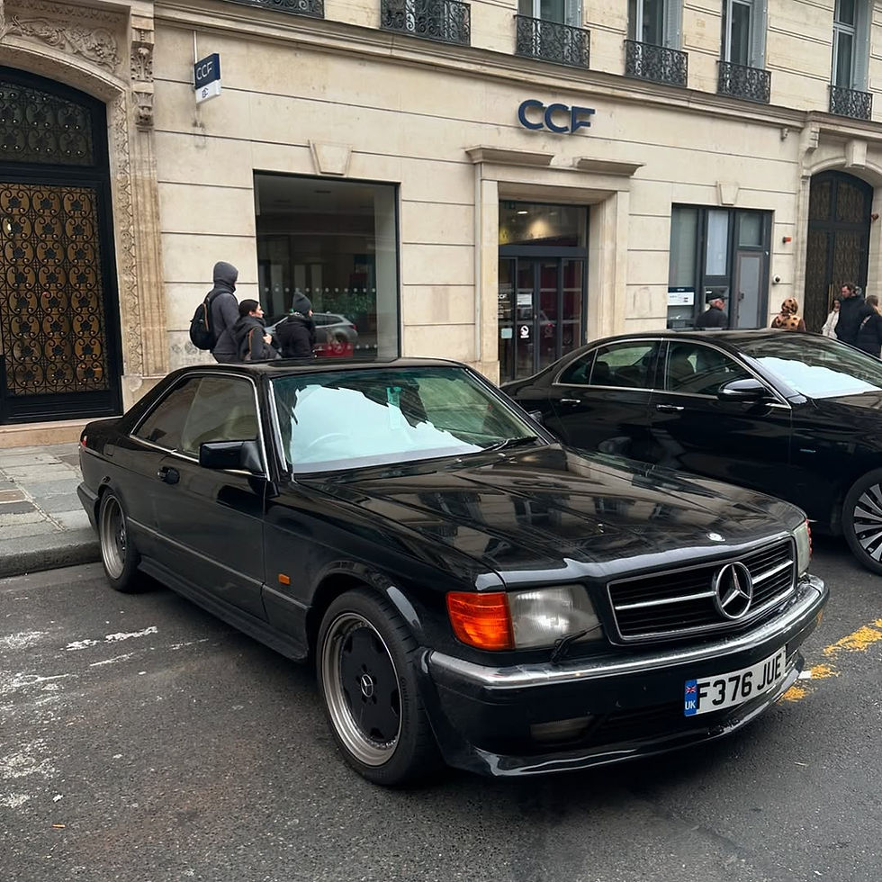 Black Mercedes-Benz SEC parked on a city street in front of CCF bank