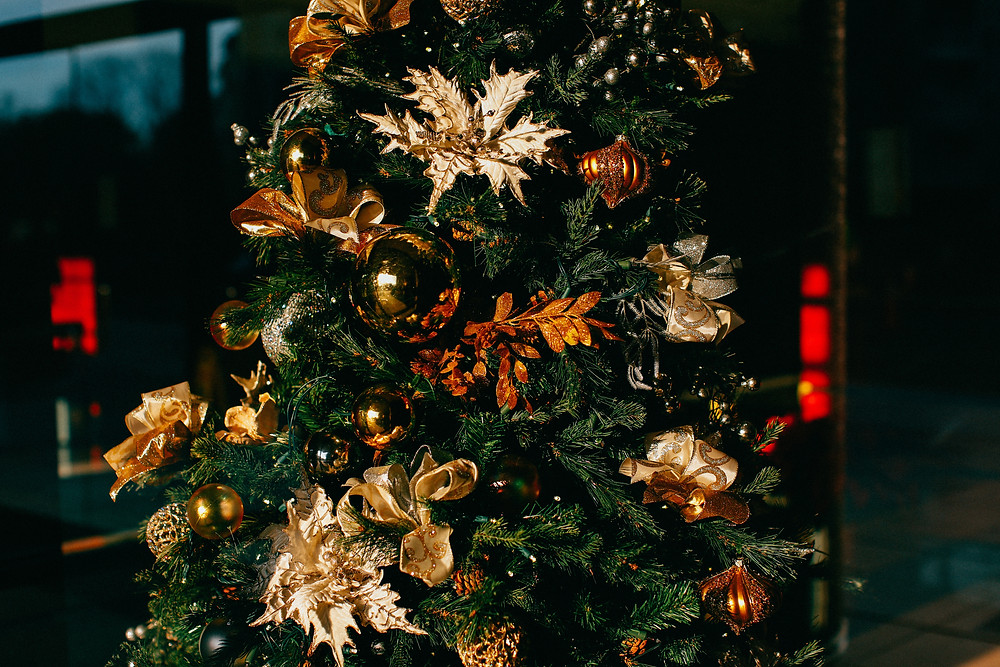 An elegant Christmas tree with gold bulbs and leaf ornaments.