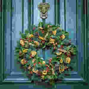 A wreath with cinnamon sticks, orange slices and pinecones on it.