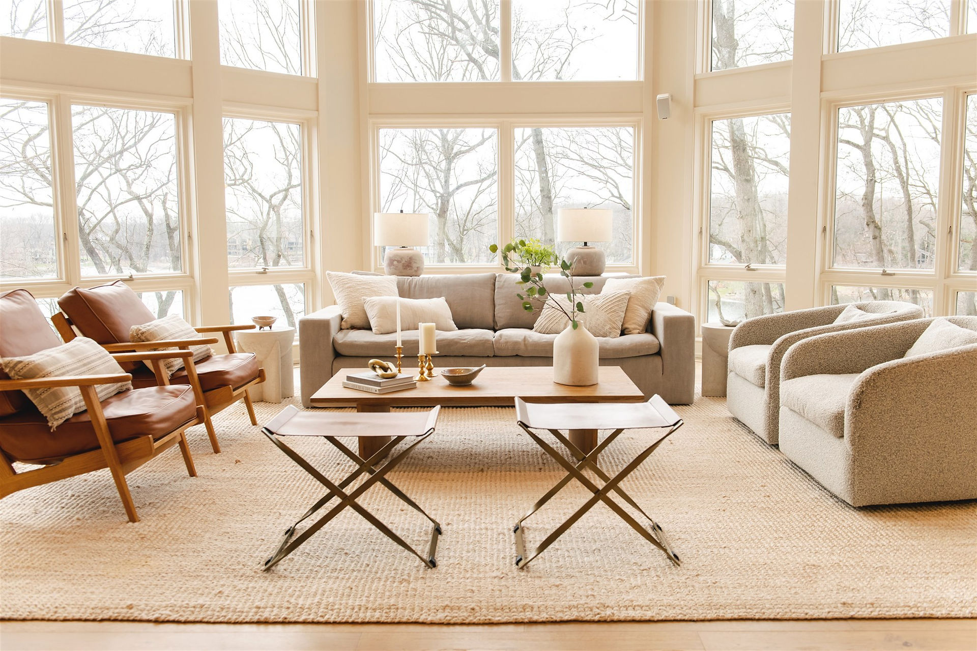 A living room in kalamazoo, michigan designed by lauren figueroa interior designer featuring neutral tones, texture, leather, and massive windows
