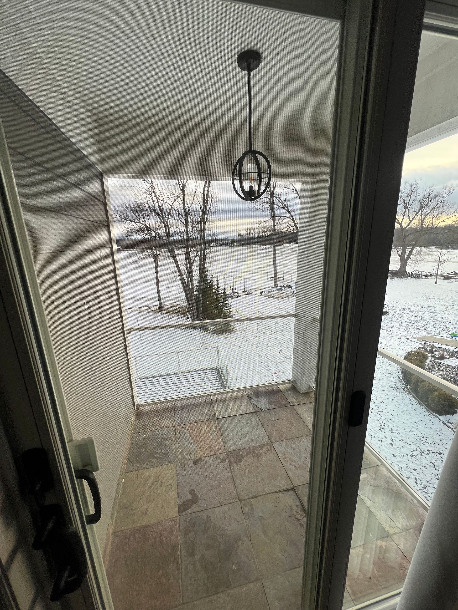 A balcony with slate flooring looking out at a snowy lake