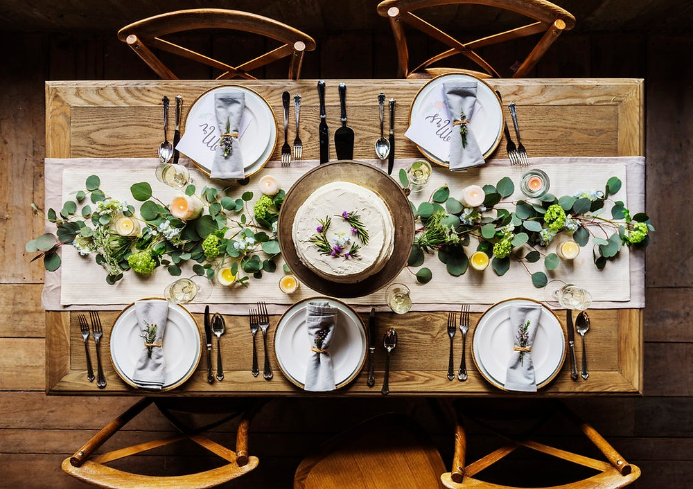 A natural Thanksgiving tablescape featuring greenery, candles, and neutral colors.