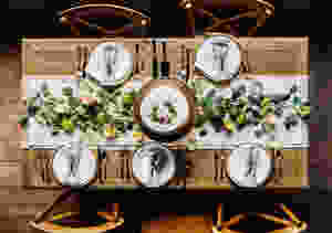 A natural Thanksgiving tablescape featuring greenery, candles, and neutral colors.