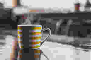 A steaming hot toddy in a yellow and white striped mug.
