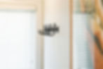 Black hooks on a white wall between partially closed blinds, creating a modern, minimalist look. No text visible.