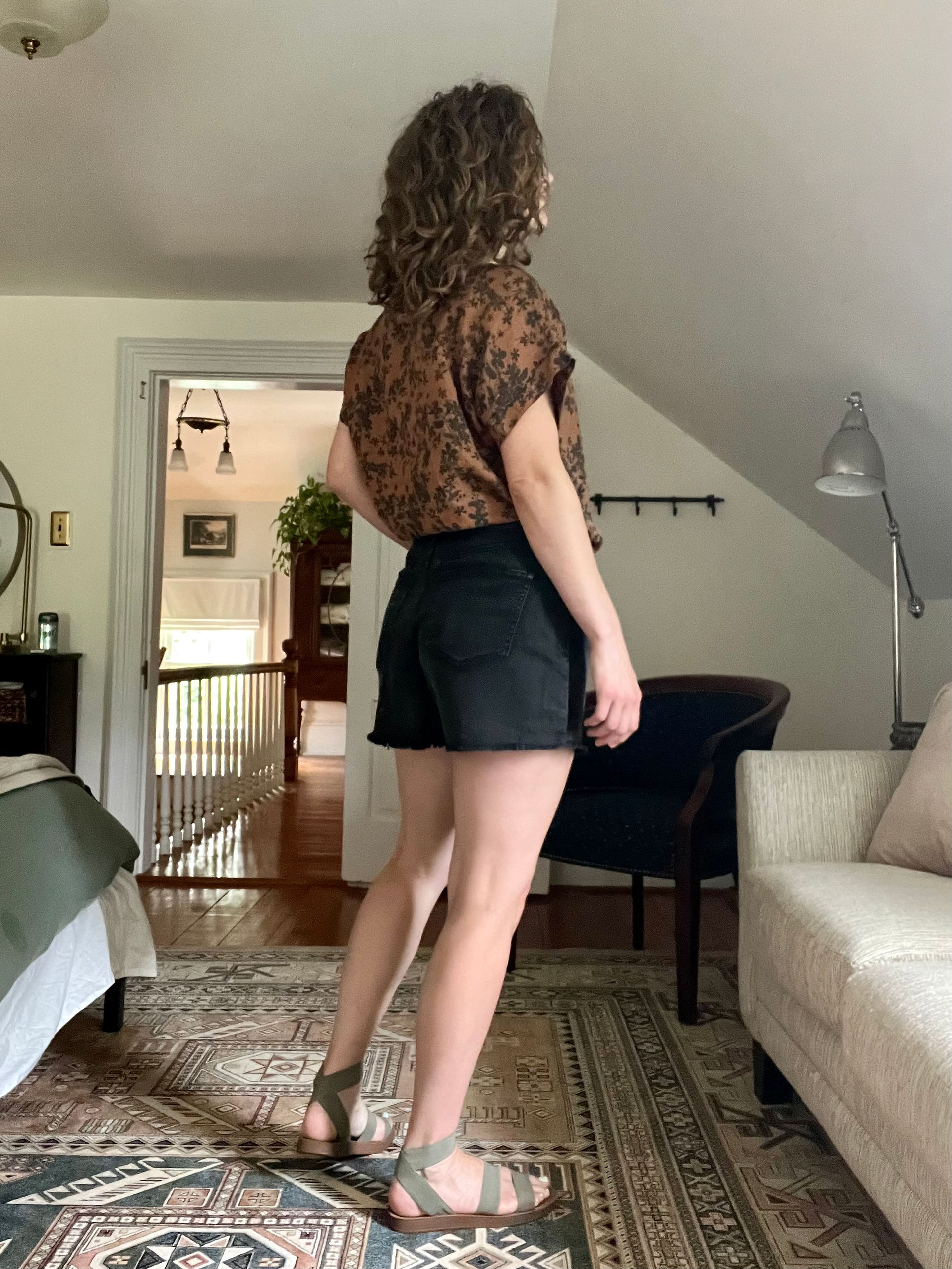 Woman wearing brown floral tunic top, black shorts, and sandals