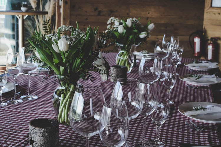 A table with a checkered cloth and tall floral arrangements.