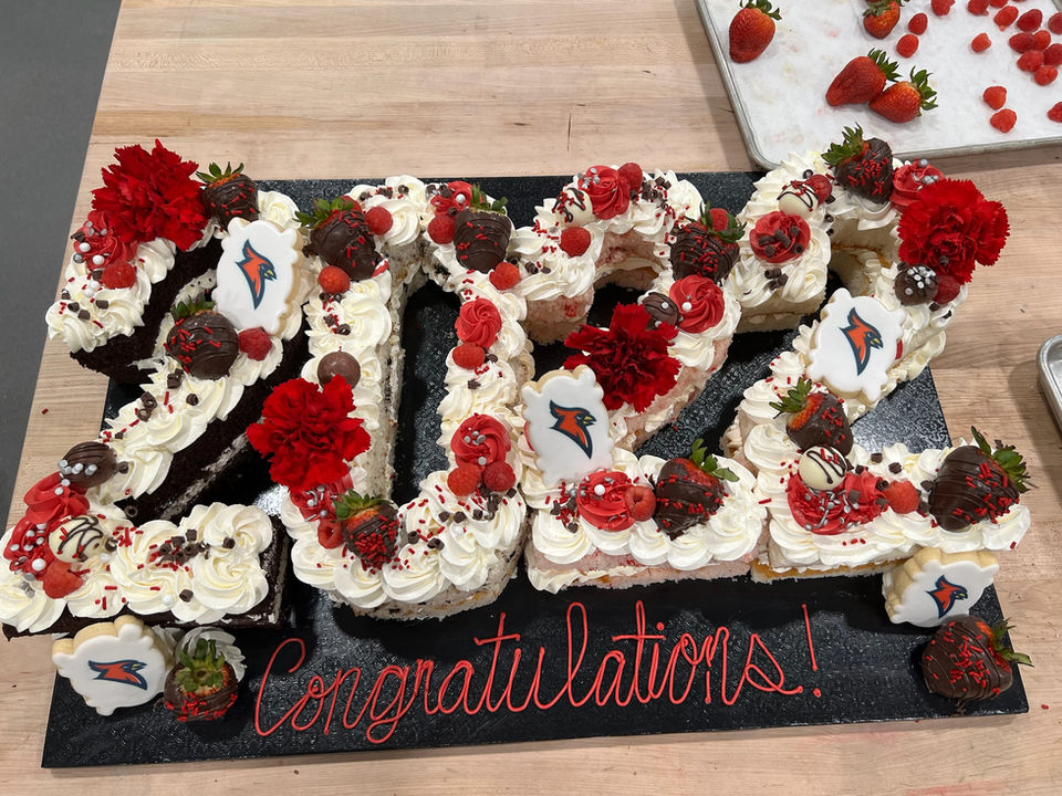 2022 shaped graduation cake topped with cookies and chocolate covered strawberries for high school grad party