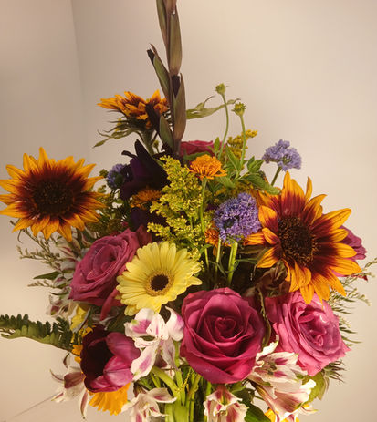 Bright wedding flower arrangement featuring sunflowers and colorful pink, yellow, purple and white blooms by Floral Fusion in Long Beach, Washington.