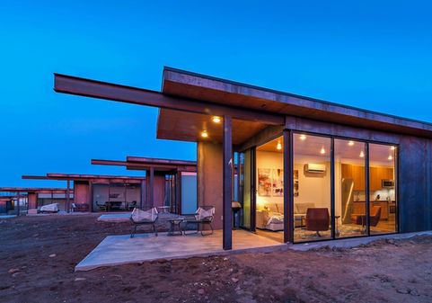 Exterior view of condo at dusk looking in to warmly lit, cozy room.