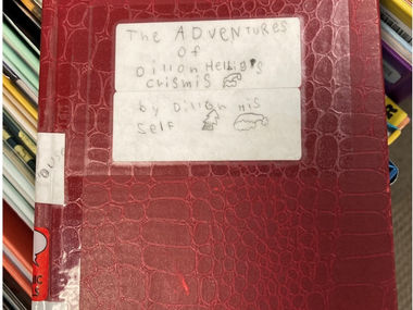 An 8-year-old slid his handwritten book onto a library shelf.