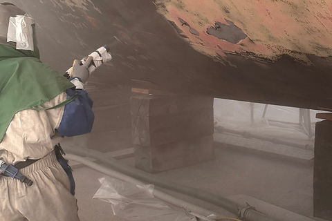 Marine sandblaster blasting underwater hull of vessel